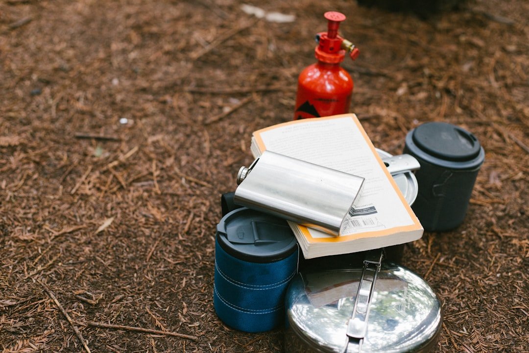 flat lay photography of hip flask, book, tiffin carrier and container tiny land